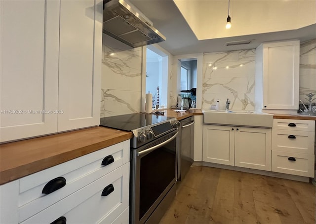 kitchen featuring sink, range hood, white cabinets, and appliances with stainless steel finishes