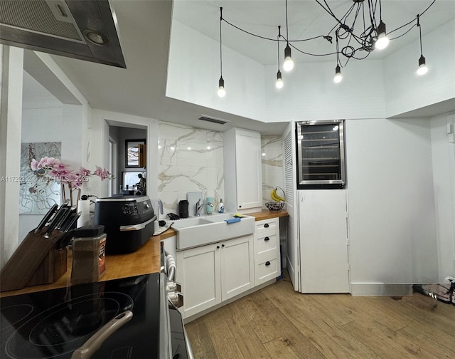 kitchen with pendant lighting, wood counters, sink, and white cabinets