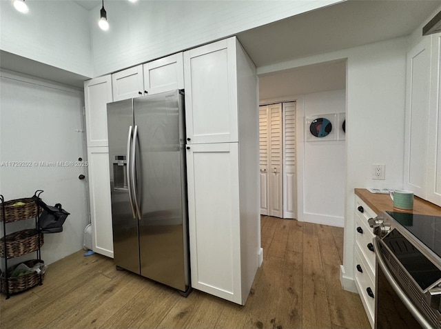 kitchen featuring stainless steel appliances, wooden counters, white cabinets, and light wood-type flooring