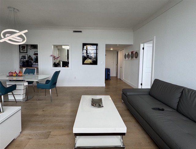 living room featuring crown molding, wood-type flooring, and an inviting chandelier