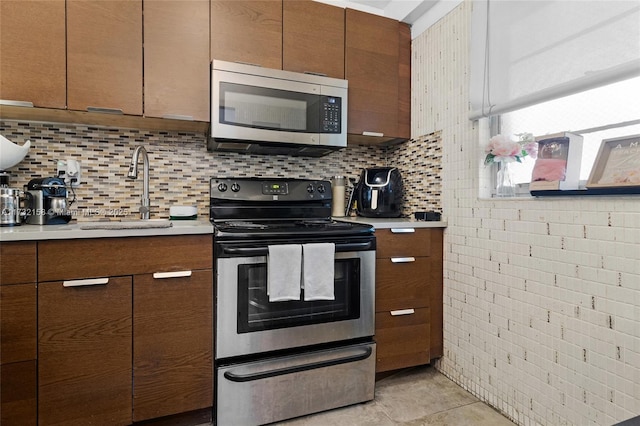 kitchen with tasteful backsplash, stainless steel appliances, sink, and light tile patterned floors