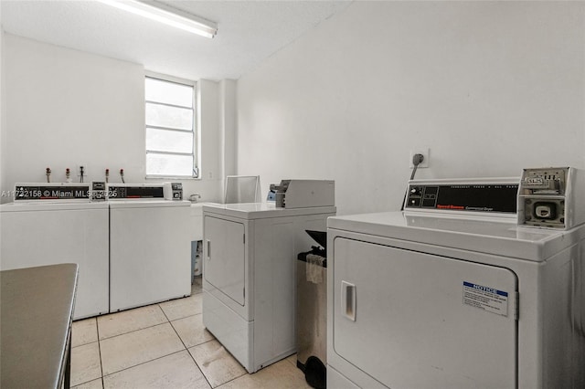 clothes washing area with light tile patterned floors and washer and clothes dryer