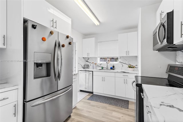 kitchen with white cabinetry, stainless steel appliances, light stone countertops, and tasteful backsplash