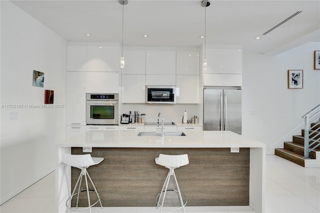 kitchen featuring light tile patterned floors, sink, hanging light fixtures, stainless steel appliances, and white cabinets