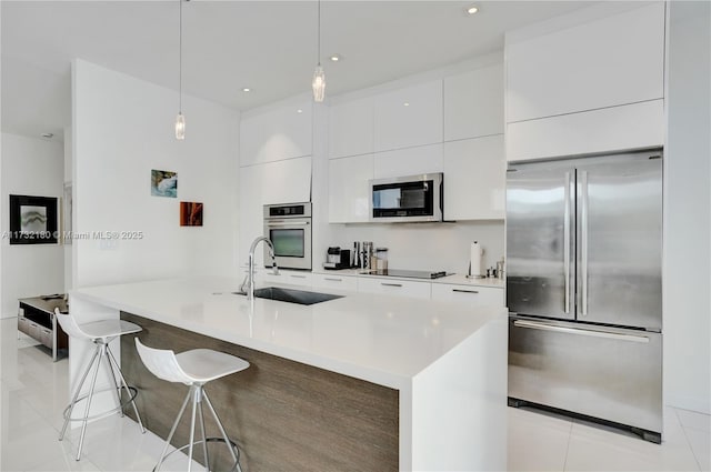 kitchen with a kitchen bar, sink, white cabinetry, decorative light fixtures, and stainless steel appliances