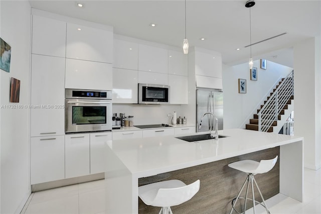 kitchen featuring decorative light fixtures, a breakfast bar area, stainless steel appliances, and a center island with sink