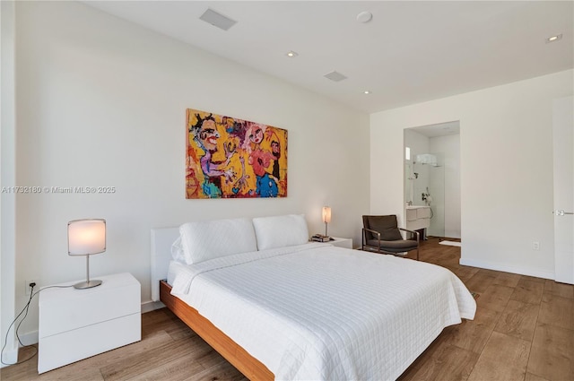 bedroom with hardwood / wood-style flooring and connected bathroom