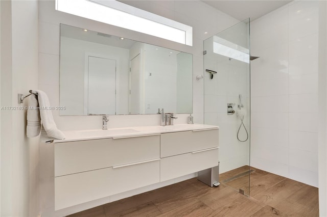 bathroom featuring hardwood / wood-style flooring, vanity, and a tile shower