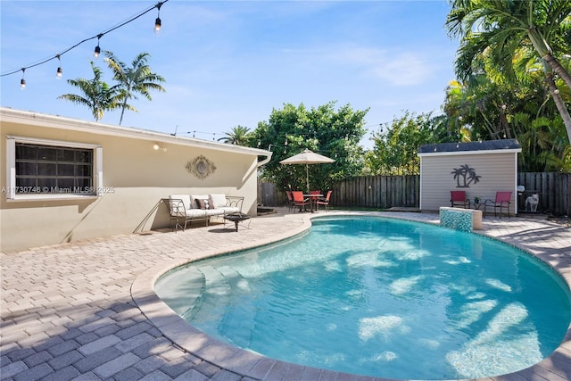 view of pool with pool water feature, a storage unit, an outdoor living space, and a patio