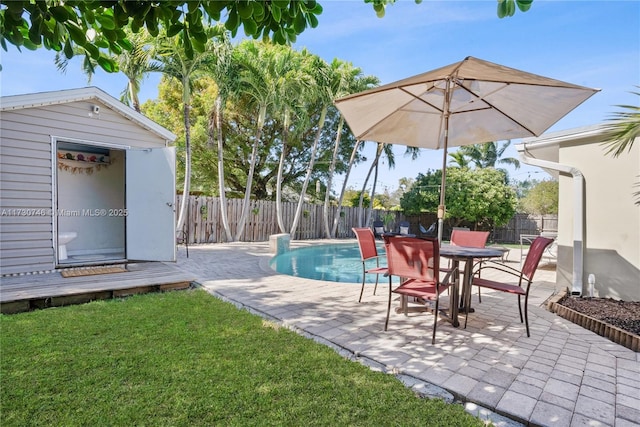 view of swimming pool featuring a lawn, an outdoor structure, and a patio