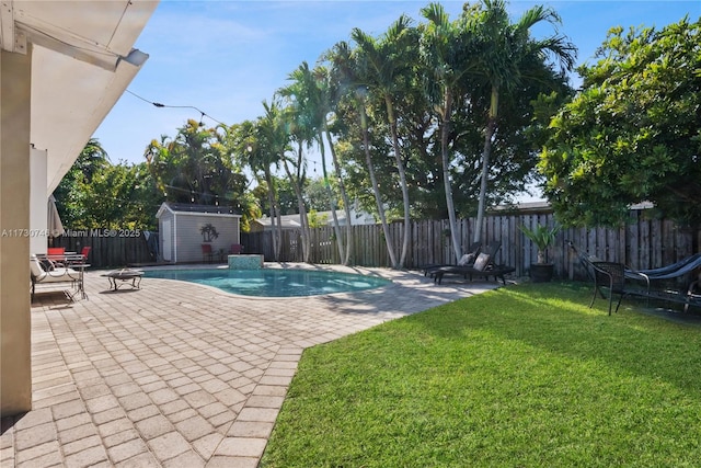 view of swimming pool featuring a patio area, a lawn, and a storage unit