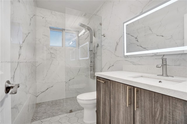 bathroom with vanity, tile walls, toilet, and a tile shower