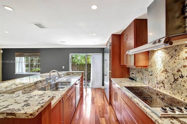 kitchen with wall chimney exhaust hood, sink, black electric stovetop, light hardwood / wood-style floors, and decorative backsplash