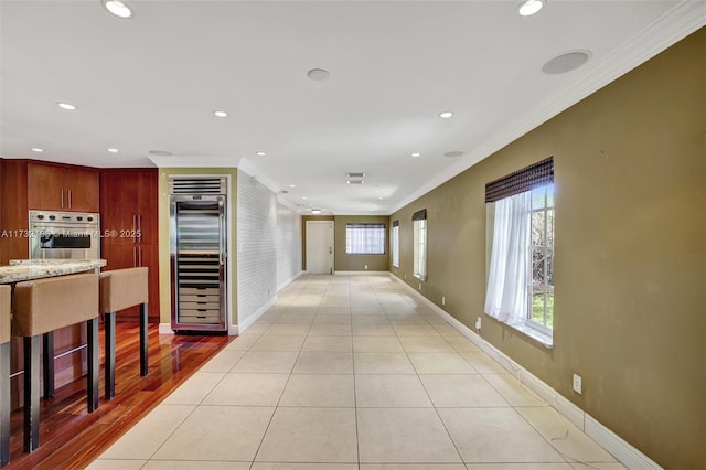 hall featuring light tile patterned floors, crown molding, and beverage cooler