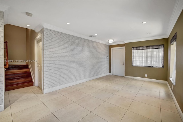 spare room with ornamental molding, brick wall, and light tile patterned floors