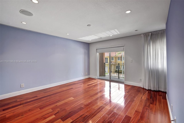 unfurnished room with hardwood / wood-style floors and a textured ceiling