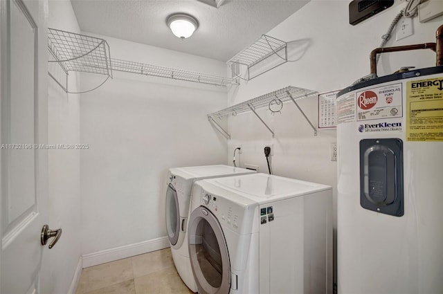 clothes washing area with electric water heater, light tile patterned floors, a textured ceiling, and washer and clothes dryer