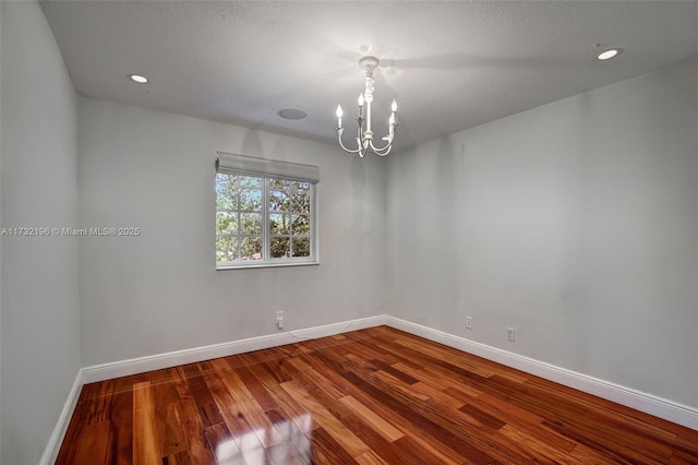 spare room featuring a notable chandelier and wood-type flooring