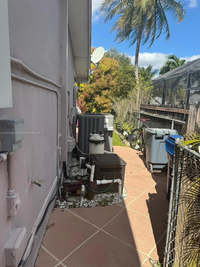 view of patio featuring central AC and glass enclosure