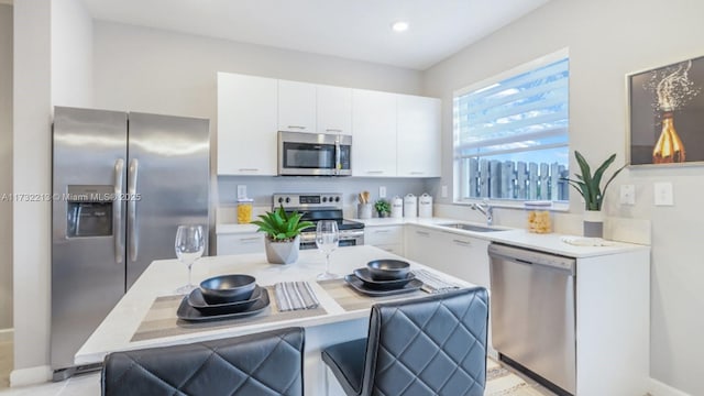 kitchen with white cabinetry, appliances with stainless steel finishes, sink, and a breakfast bar area