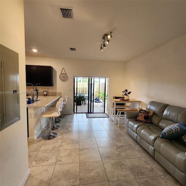 living room with light tile patterned flooring, rail lighting, and electric panel