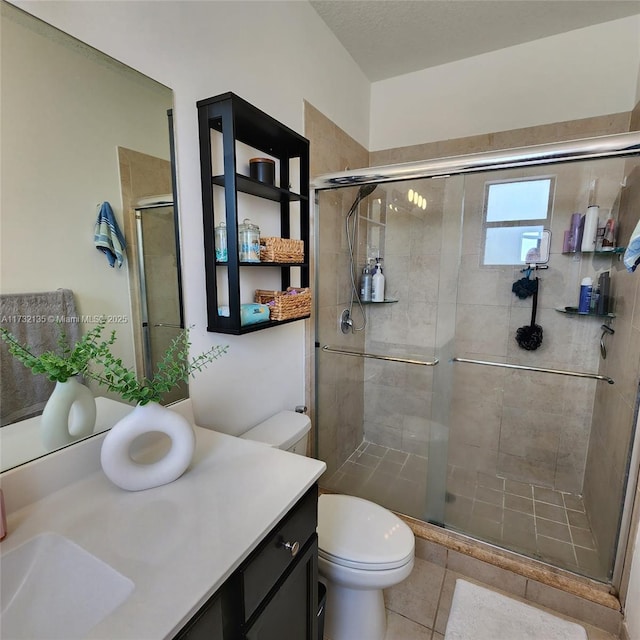 bathroom featuring walk in shower, vanity, toilet, and tile patterned flooring