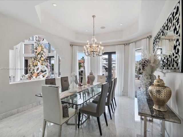 dining area with an inviting chandelier and a tray ceiling