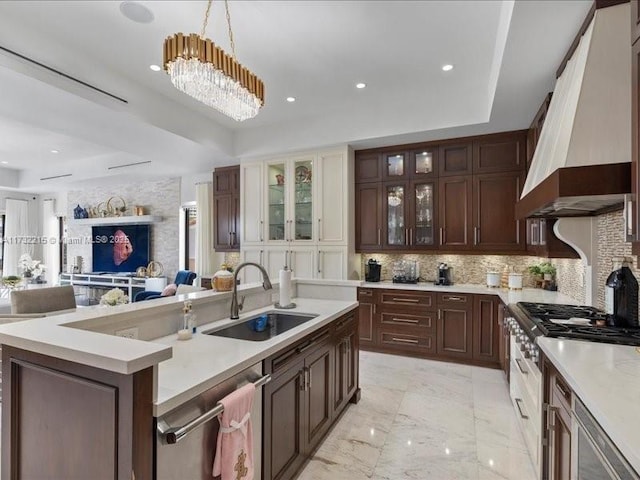 kitchen with sink, hanging light fixtures, backsplash, custom range hood, and a raised ceiling