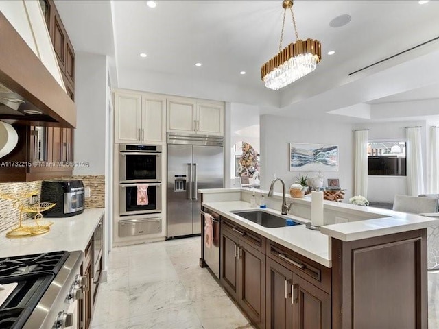 kitchen featuring appliances with stainless steel finishes, decorative light fixtures, sink, custom exhaust hood, and a center island with sink