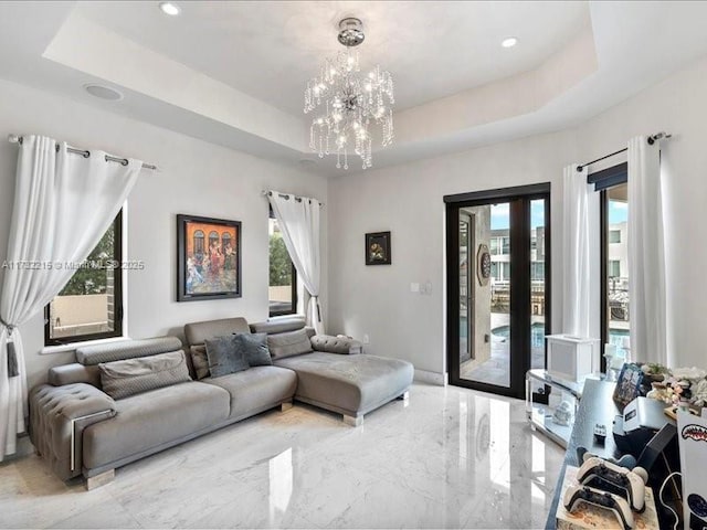 living room featuring a healthy amount of sunlight, a tray ceiling, and a chandelier