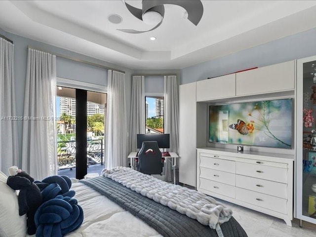 bedroom featuring ceiling fan, a raised ceiling, and access to outside