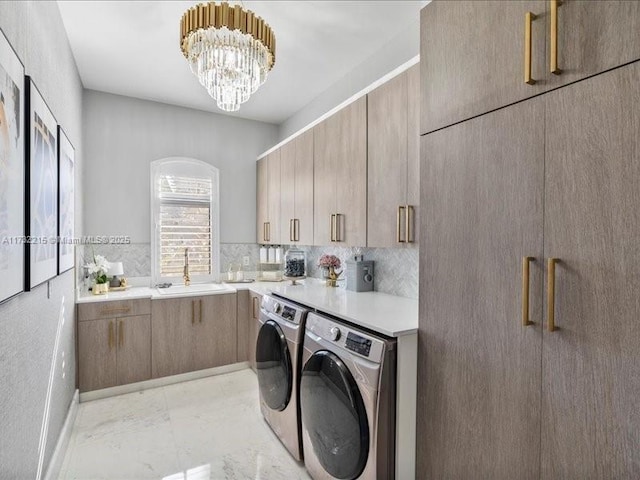 laundry area with cabinets, independent washer and dryer, sink, and a notable chandelier