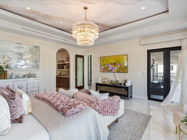 bedroom featuring french doors, a notable chandelier, a raised ceiling, and access to outside