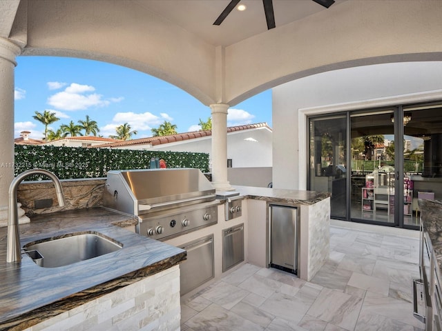 view of patio featuring ceiling fan, exterior kitchen, sink, and area for grilling