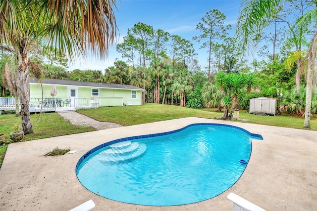 view of swimming pool featuring a lawn, a deck, and a storage unit