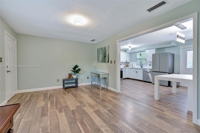 interior space with sink, a textured ceiling, and light wood-type flooring