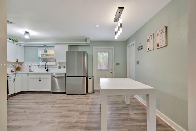 kitchen featuring white cabinetry, stainless steel appliances, sink, and light hardwood / wood-style flooring