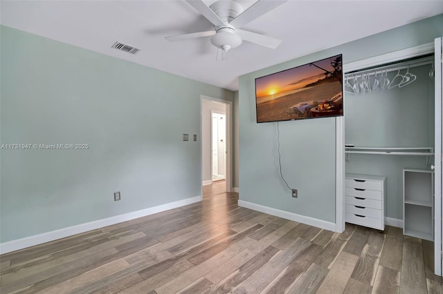 unfurnished bedroom with hardwood / wood-style flooring, ceiling fan, and a closet