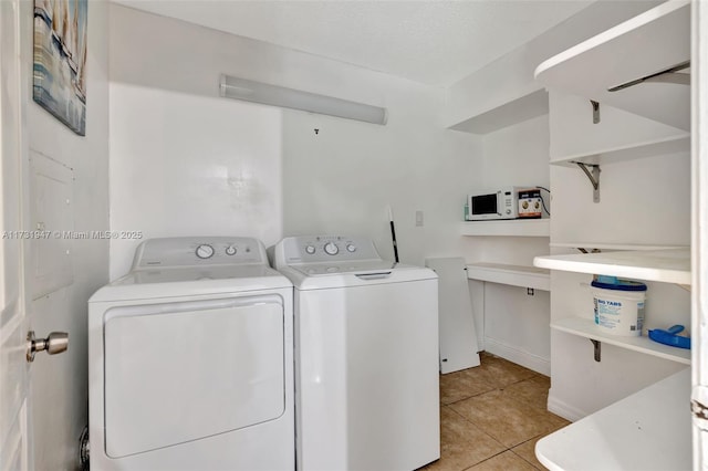 clothes washing area featuring light tile patterned flooring and washing machine and clothes dryer