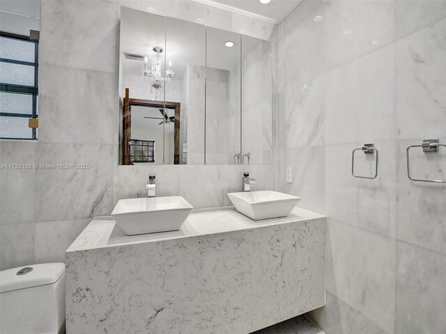 bathroom featuring tile walls, vanity, toilet, and ceiling fan