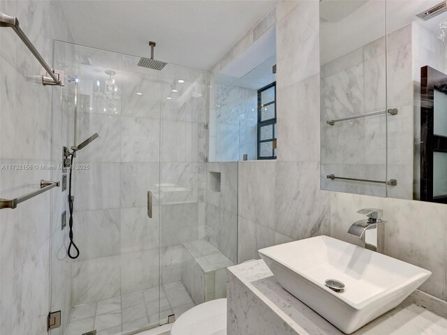 bathroom featuring toilet, a shower with shower door, sink, and tile walls