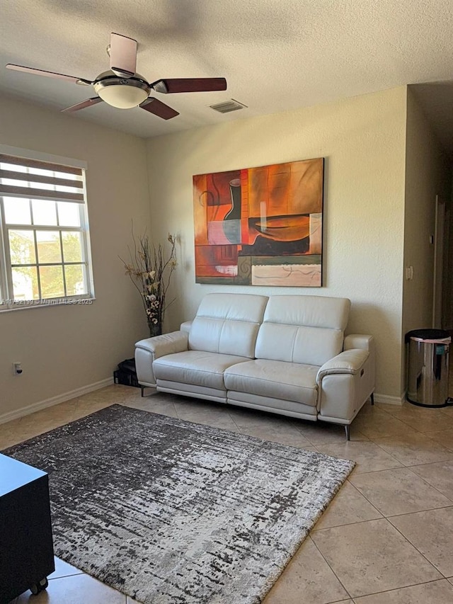 tiled living room with ceiling fan and a textured ceiling