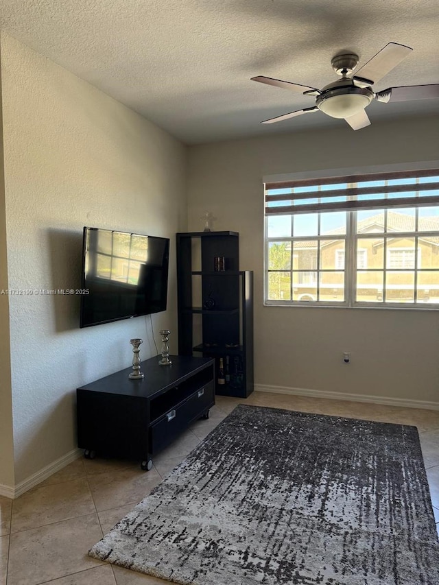 living room with light tile patterned floors, a textured ceiling, and ceiling fan