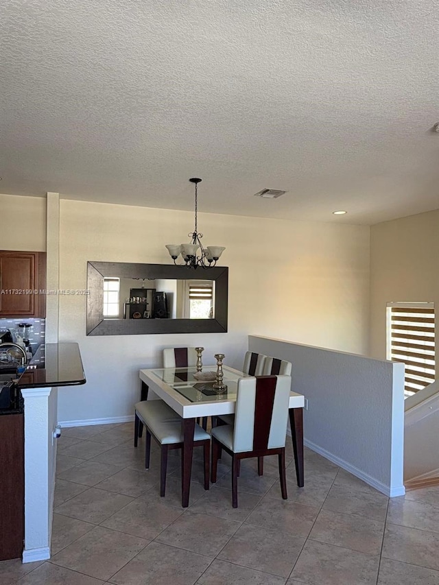 tiled dining area featuring a textured ceiling and a notable chandelier