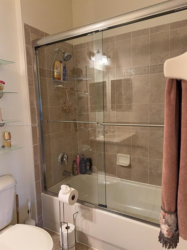 bathroom with toilet, tile patterned floors, and bath / shower combo with glass door