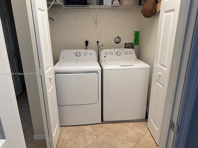 clothes washing area with washer and dryer and light tile patterned floors