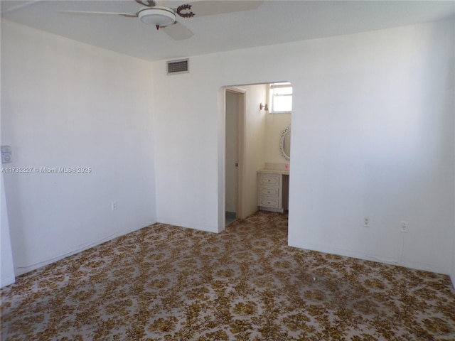 carpeted empty room featuring arched walkways, visible vents, and a ceiling fan