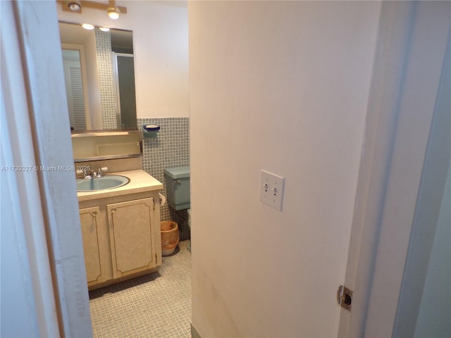 bathroom featuring toilet, vanity, and tile walls