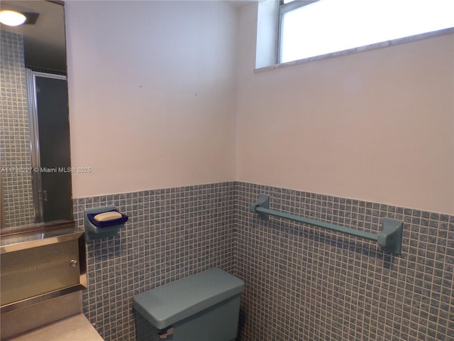 bathroom featuring tile walls and toilet