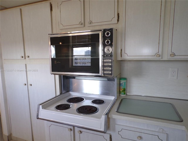 kitchen featuring black microwave, light countertops, and stovetop